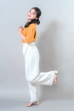 Neşeli genç kadın neşeli bir şekilde gülümsüyor, stüdyo çekimlerinde mutluluğu ve eğlenceyi ifade ediyor..