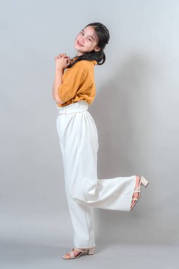 Neşeli genç kadın neşeli bir şekilde gülümsüyor, stüdyo çekimlerinde mutluluğu ve eğlenceyi ifade ediyor..