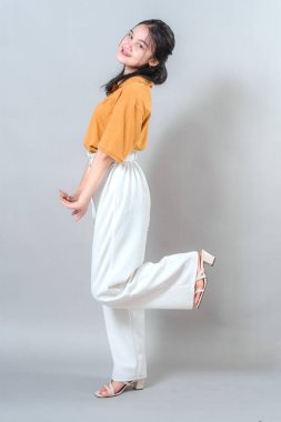 Neşeli genç kadın neşeli bir şekilde gülümsüyor, stüdyo çekimlerinde mutluluğu ve eğlenceyi ifade ediyor..