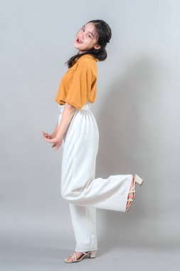 Neşeli genç kadın neşeli bir şekilde gülümsüyor, stüdyo çekimlerinde mutluluğu ve eğlenceyi ifade ediyor..