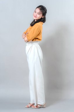 Kendine güveni tam genç bir kadın. Nazik bir yüz ifadesiyle gülümsüyor. Kolları çapraz ve vücudu hafifçe gevşemiş..