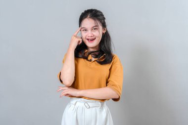 Mutlu genç bir kadın şakağını işaret ediyor, parlak bir ifadeyle gülümsüyor, zekice bir fikri ya da ilhamı simgeliyor. Yaratıcılık ve akıllı düşünce kavramları için harika..