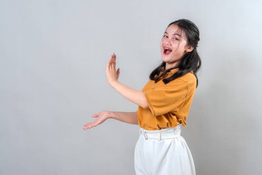 Hevesli bir yüz ifadesi olan mutlu genç Asyalı kadın bir şeyler gösteriyor. Heyecanlı ve şaşırmış görünüyor. Bu da onu promosyon ya da reklam temaları için mükemmel yapıyor..