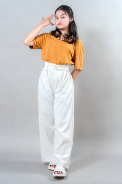 Ciddi ve kendine güveni olan genç bir Asyalı kadın, el hareketleriyle tapınağın yakınlarında poz veriyor. Stüdyo portresi kararlılık, karizma ve modern tutumu vurguluyor.