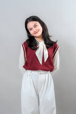 Yumuşak, tatlı bir gülümseme ve nazik bir ifadeyle genç bir Asyalı kadının portresi, sakince poz verirken başını hafifçe eğen, şefkat, sıcaklık ve dostluk saçan.