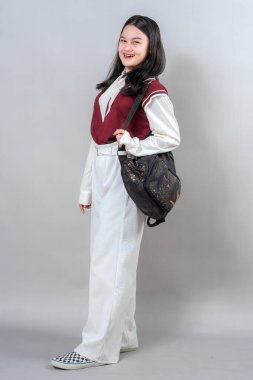 Geniş, neşeli bir gülümsemesi ve doğrudan kameraya bakan parlak gözleri olan genç bir kadın. Onun pozitif ifadesi ve rahat duruşu gençlik reklamları için ideal..