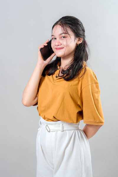 Happy young Asian woman laughing while talking on the phone. Her cheerful expression and genuine joy make this portrait ideal for advertising campaigns about connection and communication.