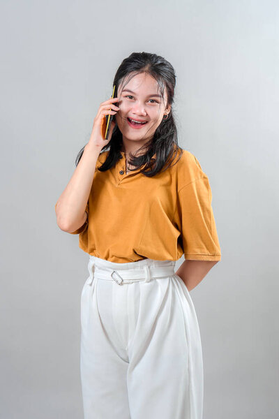 Happy young Asian woman laughing while talking on the phone. Her cheerful expression and genuine joy make this portrait ideal for advertising campaigns about connection and communication.