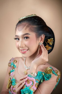 Gülümseyen Endonezyalı bir kadın çiçek desenli geleneksel kıyafetler giyiyor, zarif ve zarif bir portrede doğal güzellik, güven ve kültürel çekicilik sergiliyor..