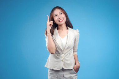 Kendine güvenen Endonezyalı bir iş kadını gülümseyerek, resmi giyinmiş, modern, yaratıcı ve profesyonel bir imaj sunan, küresel şirket ve iş teması için uygun yeni bir fikri ifade eder gibi yukarı doğru işaret ediyor..