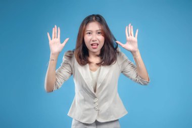 Endonezyalı bir iş kadını, resmi kurumsal kıyafetler giyerken el kaldırarak sürpriz bir yüz ifadesi sergiliyor. Küresel iş teması için profesyonel ama anlamlı bir görünüm sunuyor..