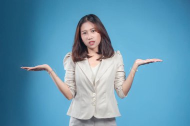 Endonezyalı bir iş kadını, resmi kurumsal giysiler giyip, küresel iş temalarına uygun profesyonel bir görünüm sunarken, omuz silkerek güvenilmez bir ifade sergiliyor..