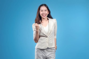 Endonezyalı bir iş kadını resmi giysiler içinde olumlu bir yumruk hareketi yaparken özgüvenle gülümserken küresel şirket, başarı ve motivasyon temalarına uygun güçlü ve profesyonel bir görünüm sunuyor..