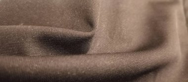 Yumuşak kıvrımlı ve görünür tekstil dokuması olan siyah yumuşak kumaşın makro görüntüsü, arka planlar, moda tasarımı ve kumaş desenleri için mükemmel.