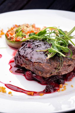 Böğürtlen soslu et ve beyaz tabakta sebze