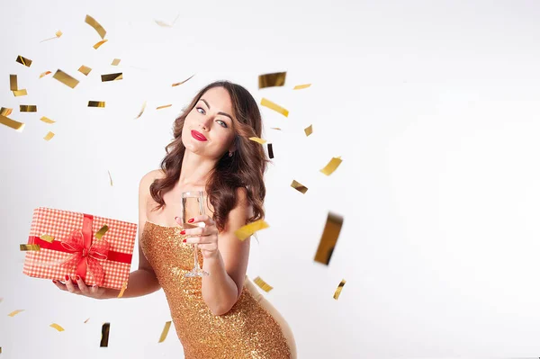 Giovane donna in possesso di una scatola regalo e beve champagne, divertendosi con coriandoli d'oro — Foto Stock