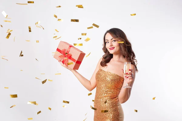 Giovane donna in possesso di una scatola regalo e beve champagne, divertendosi con coriandoli d'oro — Foto Stock