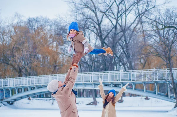 Family have fun on a frozen lake in the park against the background of the bridge — Photo