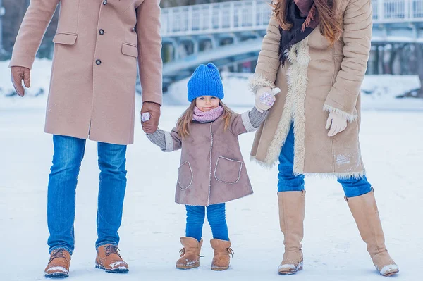 Little girl holding her parents in winter on the background of a frozen lake and bridge — Photo