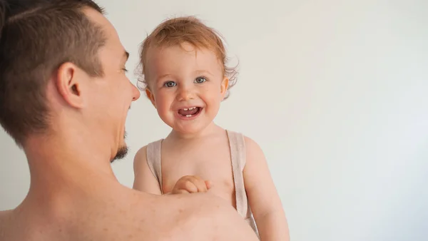 Padre che tiene un tenero bambino sorridente tra le braccia su uno sfondo bianco Immagine Stock