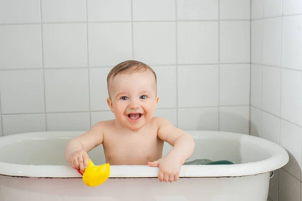 Piccolo bambino felice si bagna in una vasca da bagno Immagine Stock