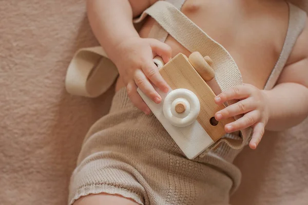Houten speelgoedcamera in de handen van een baby Stockfoto
