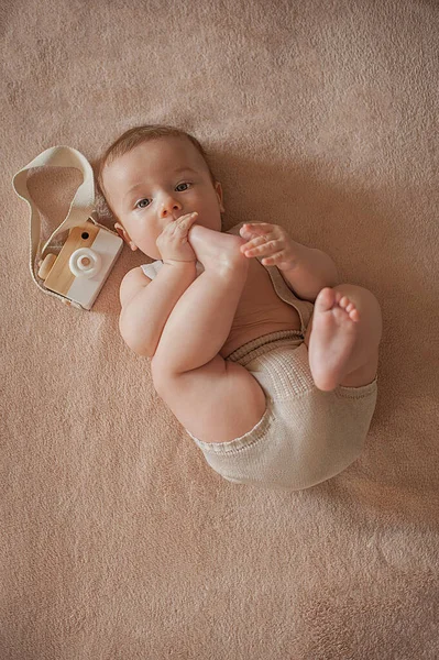 De baby zuigt teen ligt op een beige achtergrond Stockfoto