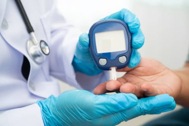 Diyabet tedavisinde kan şekeri seviyesini kontrol etmek için dijital glikoz ölçer kullanan Asyalı doktor.