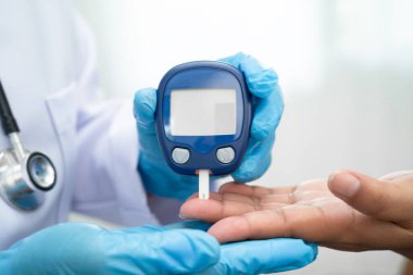 Diyabet tedavisinde kan şekeri seviyesini kontrol etmek için dijital glikoz ölçer kullanan Asyalı doktor.