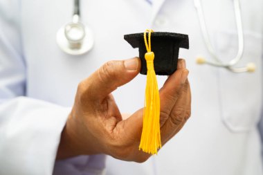 Hastanede mezun şapkası tutan Asyalı kadın doktor. Tıp eğitimi almış..