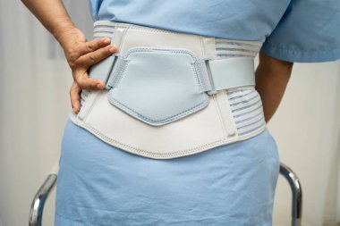 Asya baş ağrısı. Esnek destek kemeri takıp yürüteç takıyor..