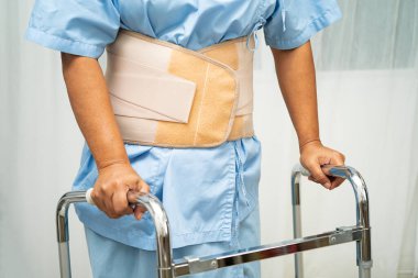 Asya baş ağrısı. Esnek destek kemeri takıp yürüteç takıyor..