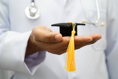 Hastanede mezun şapkası tutan Asyalı kadın doktor. Tıp eğitimi almış..