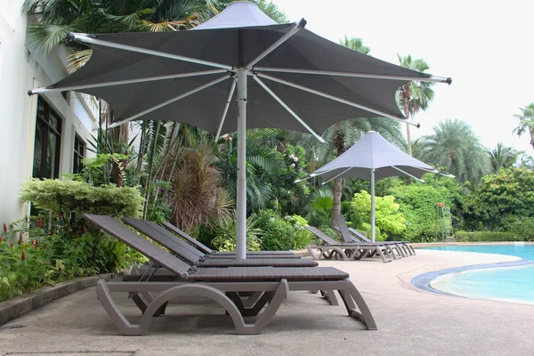 relaxing rattan chairs with a big umbrella beside the swimming pool