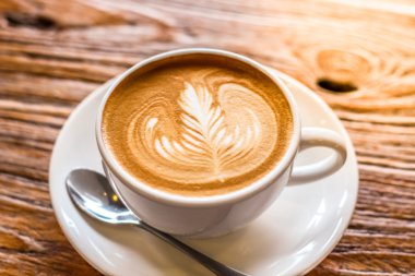 latte sanat kaşık ve plaka üzerinde kahverengi ile kahve fincan kabuk güzel doku arka plan ile ılık ışık