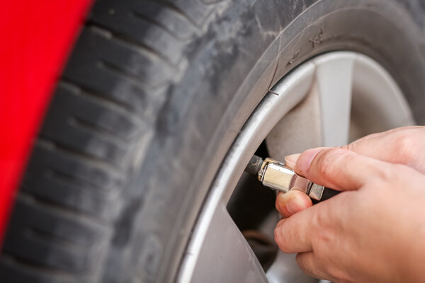 Filling air into a grungy car tire to increase pressure 