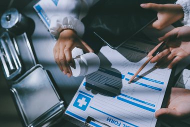 Two doctors and a female nurse meet at a table in the hospital, collaborating on medical tasks using laptops and computers