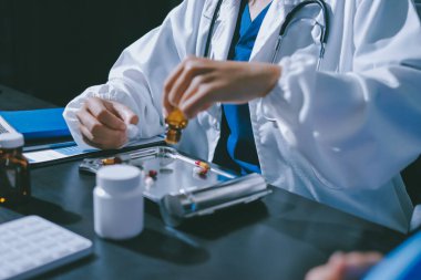 Elinde ilaç şişesi olan kadın doktor hastanın yan etkileri için ilaç kalitesini kontrol ediyor ve hasta bilgilerini hastanede kaydediyor. tıbbi ve sağlık hizmetleri kavramı