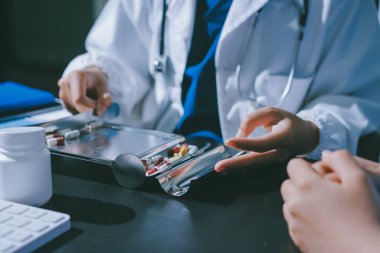 Elinde ilaç şişesi olan kadın doktor hastanın yan etkileri için ilaç kalitesini kontrol ediyor ve hasta bilgilerini hastanede kaydediyor. tıbbi ve sağlık hizmetleri kavramı