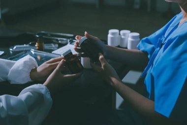 Elinde ilaç şişesi olan kadın doktor hastanın yan etkileri için ilaç kalitesini kontrol ediyor ve hasta bilgilerini hastanede kaydediyor. tıbbi ve sağlık hizmetleri kavramı