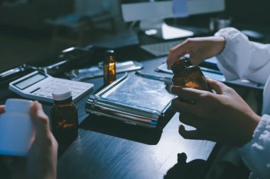 Elinde ilaç şişesi olan kadın doktor hastanın yan etkileri için ilaç kalitesini kontrol ediyor ve hasta bilgilerini hastanede kaydediyor. tıbbi ve sağlık hizmetleri kavramı