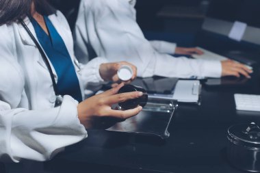 Two doctors and a female nurse meet at a table in the hospital, collaborating on medical tasks using laptops and computers
