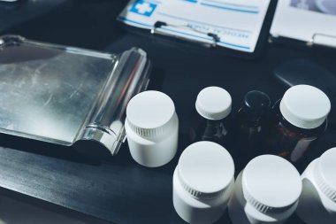 Two doctors and a female nurse meet at a table in the hospital, collaborating on medical tasks using laptops and computers