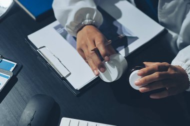 Two doctors and a female nurse meet at a table in the hospital, collaborating on medical tasks using laptops and computers