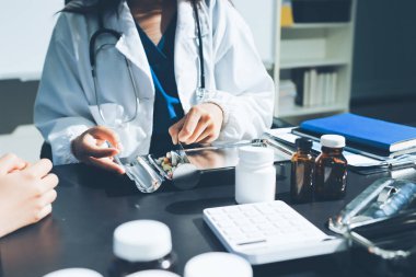 Elinde ilaç şişesi olan kadın doktor hastanın yan etkileri için ilaç kalitesini kontrol ediyor ve hasta bilgilerini hastanede kaydediyor. tıbbi ve sağlık hizmetleri kavramı