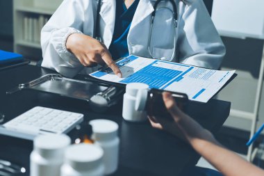 Elinde ilaç şişesi olan kadın doktor hastanın yan etkileri için ilaç kalitesini kontrol ediyor ve hasta bilgilerini hastanede kaydediyor. tıbbi ve sağlık hizmetleri kavramı