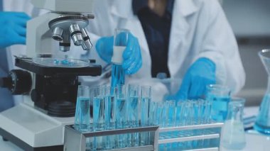 Laboratuvarda mikroskopla test tüpleri tutan bilim adamı