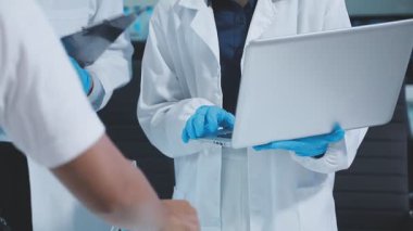 Laboratuvar önlüklü bilim adamı dijital tablet ve mikroskop kullanıyor.