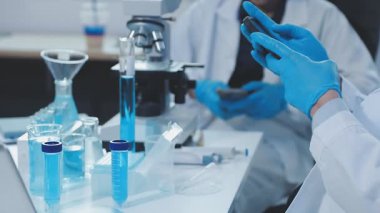 Bilim adamı elinde sıvı ile test tüpleri tutuyor.