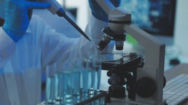 Kimya laboratuvarında mikroskop tutan ve sıvıyı analiz eden bir bilim adamı..